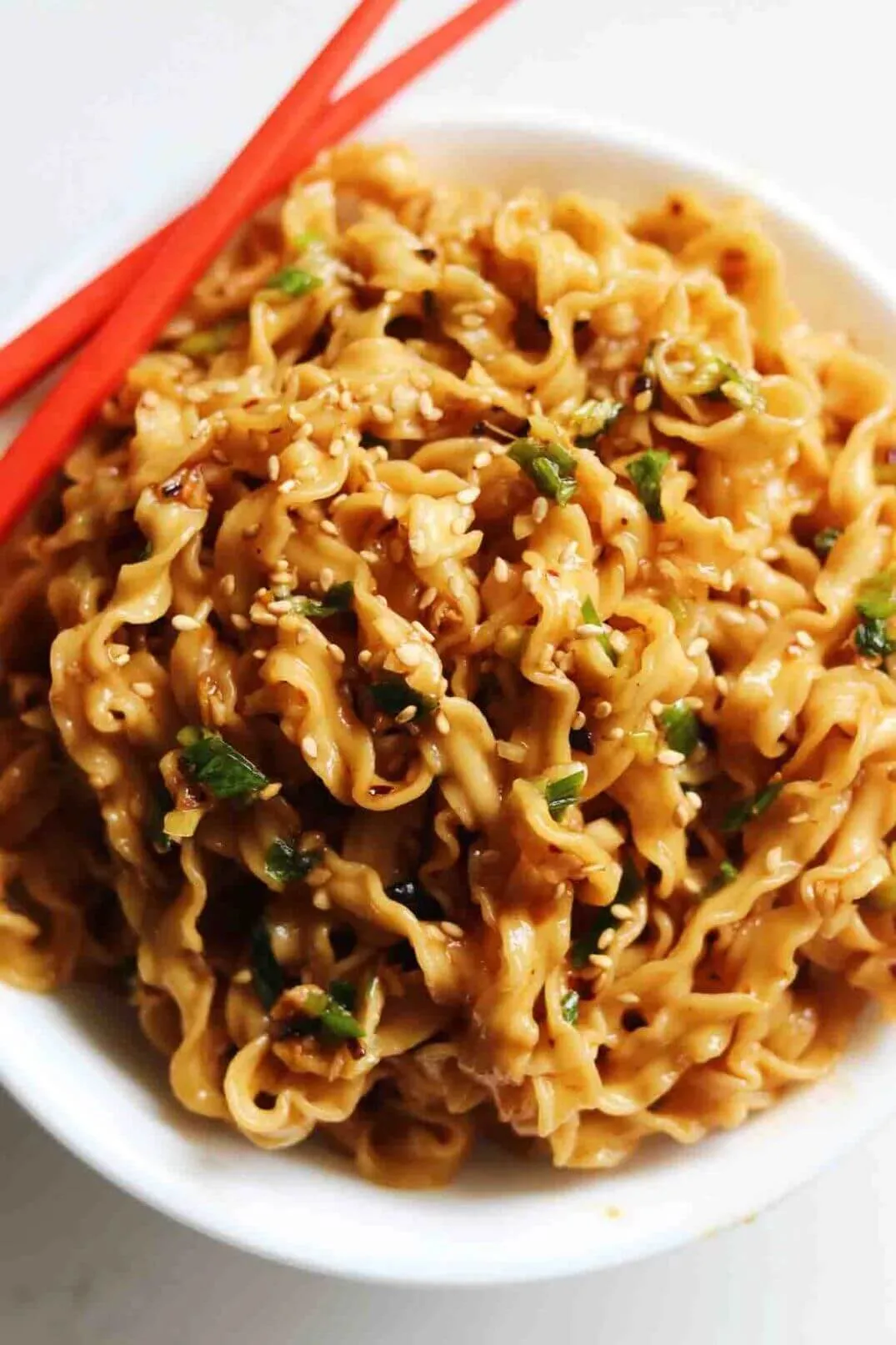 Chinese hand-pulled noodles tossed in chili oil, sesame, and scallions with red chopsticks
