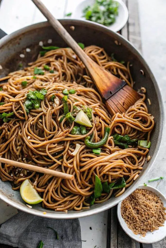 Sesame Soba Noodles Close-up of sesame soba noodles garnished with lime, scallions, and sauce
