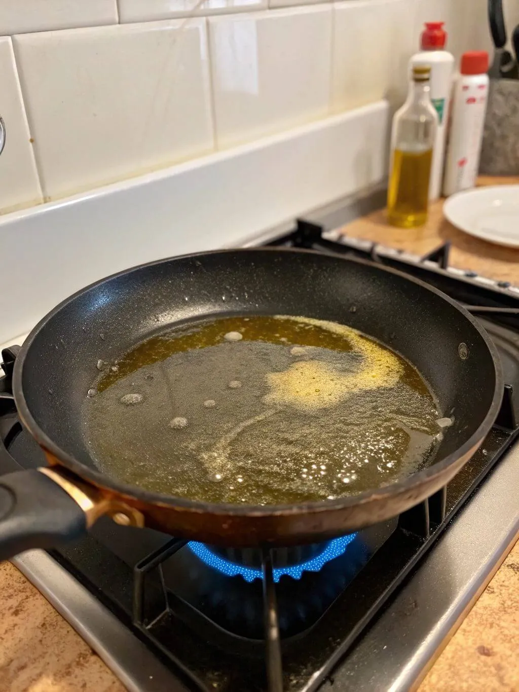 Heat oil in a skillet over medium-high heat Oil and what appears to be butter are sizzling in a black skillet on a gas stove burner set to medium-high heat.